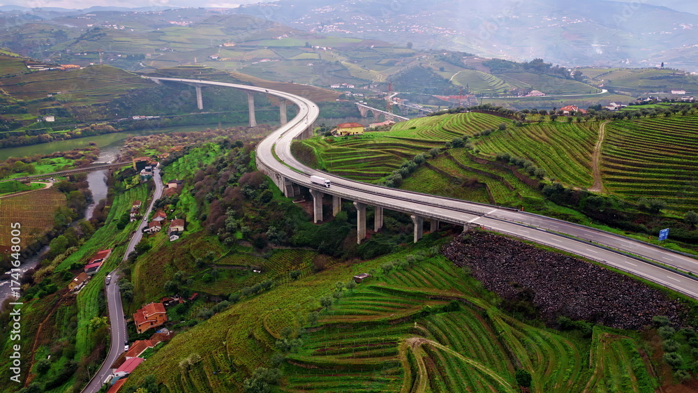 Obraz premium Highway bridge crossing terraced fields in mountain valley. Drone transport line