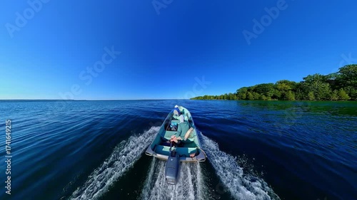 Fishing boat gliding at inland lake of Manitoulin Island. Water sport and fishing. Moving motor boat with man and woman anglers during vacation. Angling from a boat hobby fishing game.
