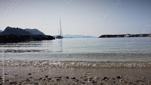Static shot of sea waves and shoreline in Parga Greece. Gentle water movement, small pebbles and reflection of morning light create relaxing Mediterranean beach scene.