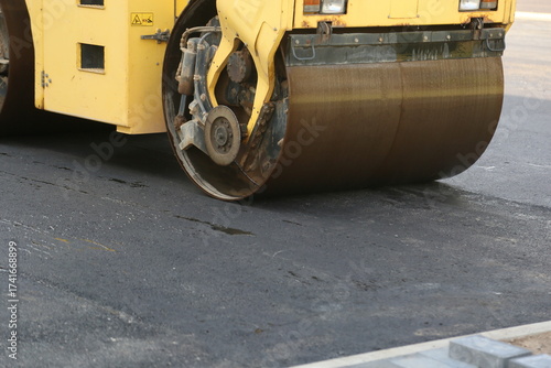 Close-up of a road paver's front wheel on freshly laid asphalt, construction and roadwork concept