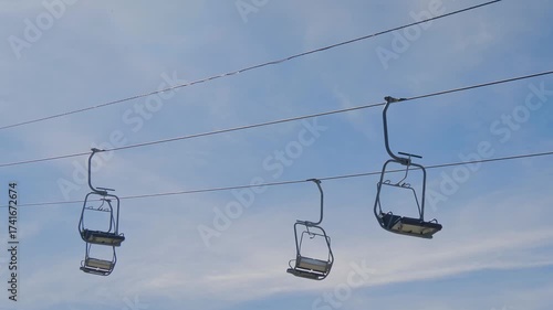 Empty chairlifts at the summit of Mount Babadag, moving against blue sky with clouds in Mugla, Turkey. Mountain transport, tourism and scenic landscape concept