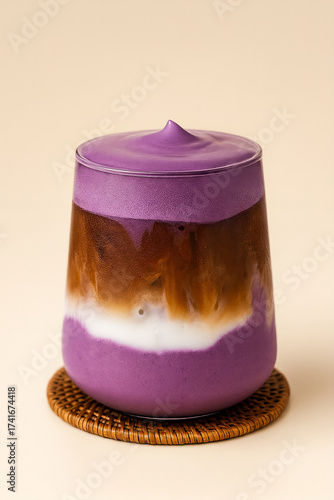 Ube latte with layered purple yam, milk, and coffee in a clear glass, isolated background