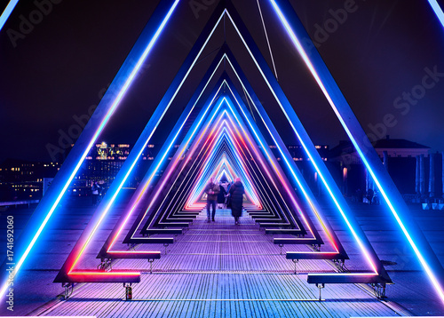 A glowing tunnel of triangles warps perception. Blurred figures drift like spectral dogs or people through a lucid dream, echoing LSD 's kaleidoscopic hallucinations and altered states of reality