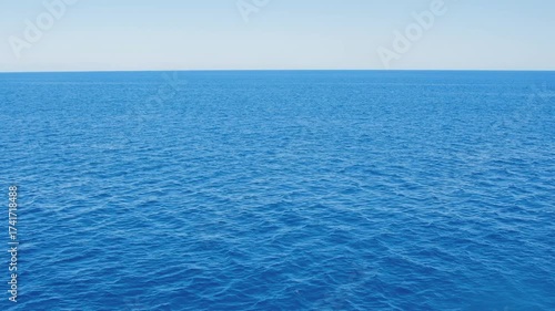 Detailed view of the ocean surface texture on a bright, sunny day. The vibrant azure and cobalt blue water is gently moved by a breeze, creating subtle waves.