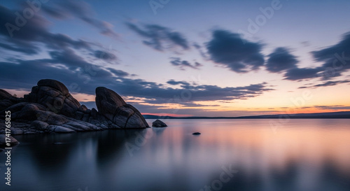 Serene Sunset over Rocky Shoreline, Blurry Water Reflections