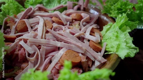 Detail of hands placing and spreading ham slices over clay plate during Guatemalan fiambre preparation