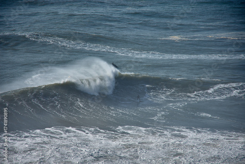 Panoramic view from the top of Nazare with surfers challenging the giant waves in a natural Atlantic setting in Portugal