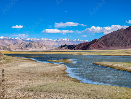 Schilderij op canvas Path to Umling La, world's highest motorable pass, with meandering river through vast Ladakh valley flanked by rugged mountains under clear blue skies, captured October 5, 2025