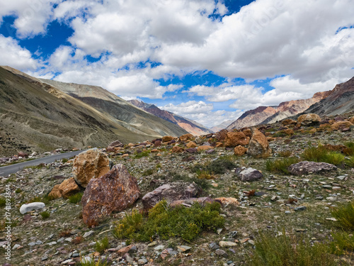 Fényképezés Martian-like vistas in Zanskar Valley, with surreal red rock formations and scattered boulders dotting the arid terrain under a vast orange-tinged sky, captured October 05, 2025