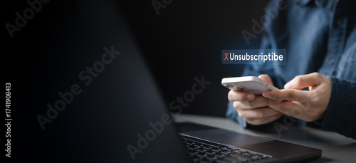 Person holding a smartphone with unsubscribe notification on screen, symbolizing cancellation of subscription, stopping recurring payments, account termination, and control over digital service plans.