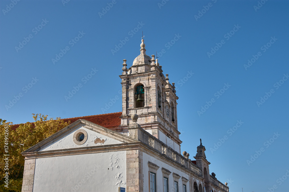 Fototapeta premium Facade of the Sanctuary of Nossa Senhora de Nazare with symmetrical towers and a blue sky, a Portuguese pilgrimage site