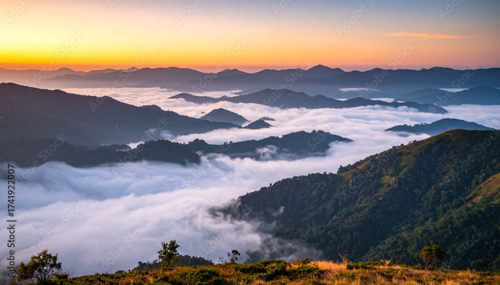 Obraz premium A misty mountain valley at dawn, with layers of soft clouds drifting