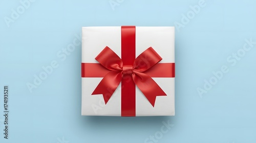 White gift box wrapped with a vibrant red satin ribbon and bow placed on a soft blue background, creating a clean festive presentation ideal for celebration, holiday design, and elegant product visual