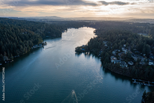 Bild auf Leinwand Aerial drone picture of Lake Oswego, Oregon, showing calm blue water surrounded by dense forest and residential houses, real estate, on a clear sunny evening at sunset