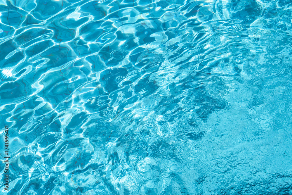 Obraz premium Clear blue water surface with sunlight reflections with ripple texture pattern in swimming pool. for summer background,Water splash with light effect for spa,vacation,tropical design,relaxation