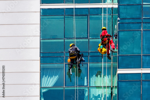 Workers, climbers wash windows of skyscraper.