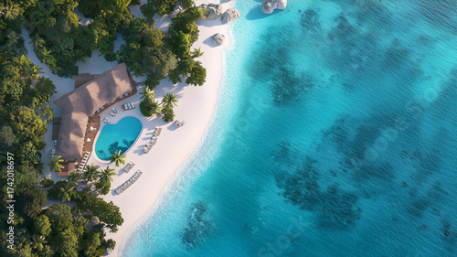 Serene Aerial View of Tropical Beach with Crystal Clear Water and Luxurious Resort Pool Surrounded by Lush Greenery and White Sand
