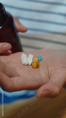 Vertical Screen : Sick asian young lady holding pill take a look medicine sit on couch at home night. Girl taking medicine after doctor order, quarantine at home, social distancing healthcare concept.