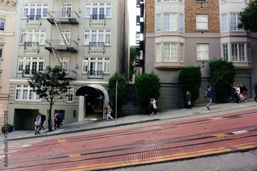 San Francisco street with people walking up and down the steep slopes, tram track in foreground