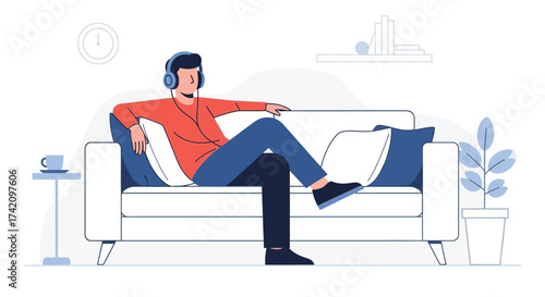 Young man with headphones on is relaxing comfortably on sofa in minimalist living room, enjoying music and moment peace and quiet