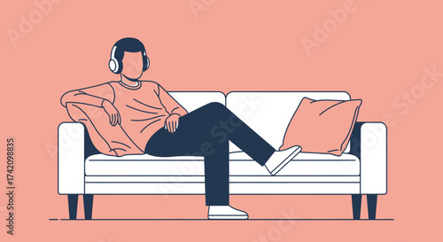 Man wearing headphones sits on couch with his legs crossed, enjoying music or podcast in relaxed pose