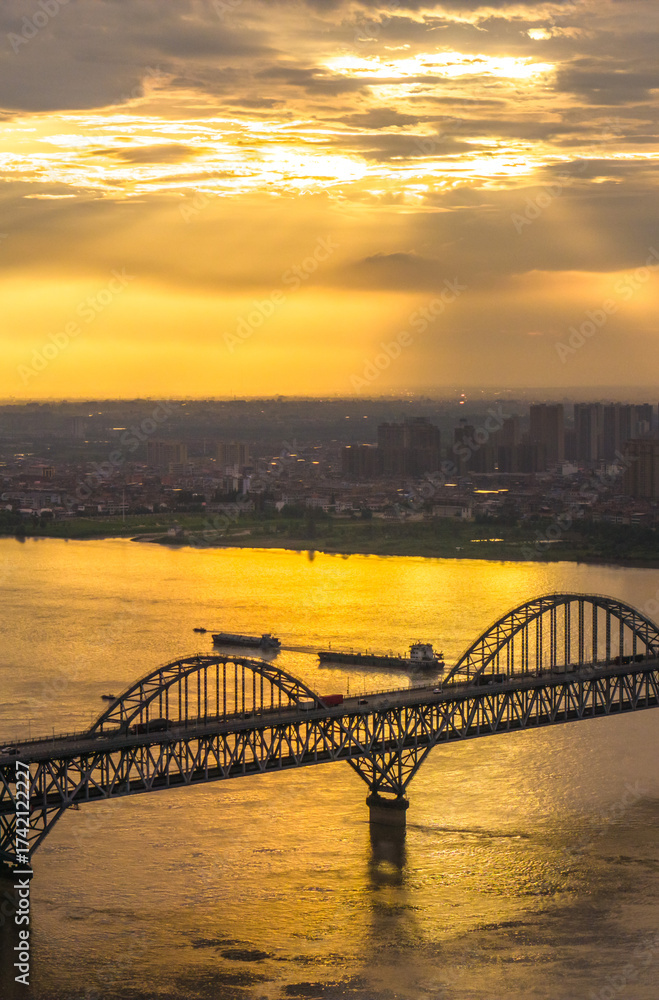 Fototapeta premium The Yangtze River and its shipping vessels, bathed in the glow of the setting sun, are located in Jiujiang, a historical and cultural ancient city in eastern Asia, Jiangxi Province, China.