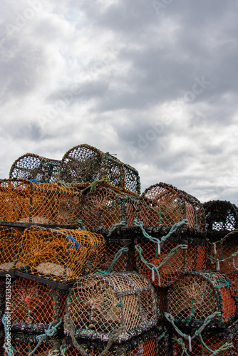 Stack of colourful Scottish lobster pots on a quay on a cloudy day