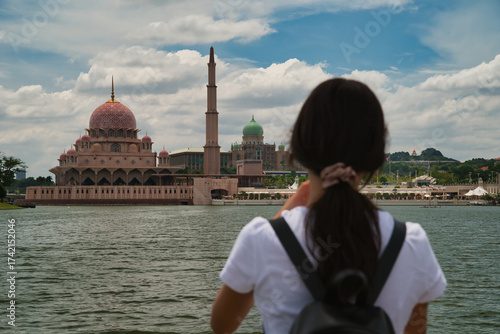 Photography Asian girl taking a photo with her smartphone on a boat with the Putra Mosque in the background