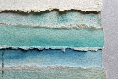 A close-up view of layered, torn paper strips, displaying a soft gradient of cool blue tones.