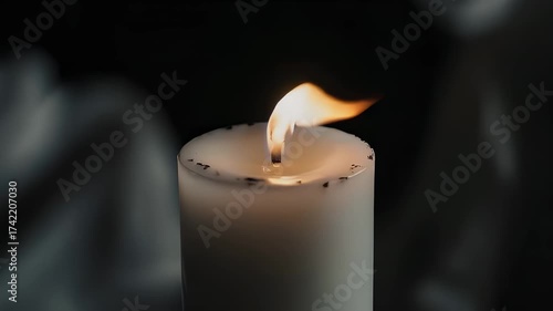 Close Up of a White Candle with a Warm Flickering Flame in a Dark Moody Background with Subtle Gray Hues Creating an
