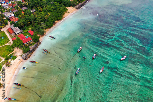 Traditional catamarans and fishing boats on Weligama Beach, Sri Lanka—drone shot of ocean, palms, and local culture