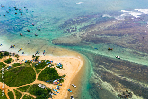 Traditional catamarans and fishing boats on Weligama Beach, Sri Lanka—drone shot of ocean, palms, and local culture