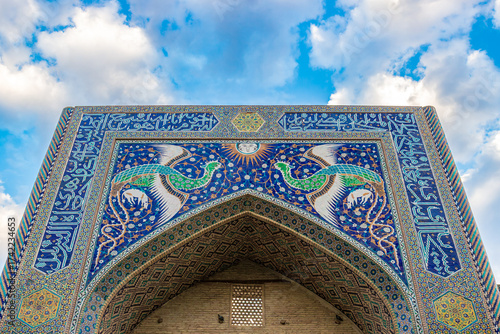 Colorful Portal of the Nadir Devanbegi Madrasah in Bukhara, Uzbekistan. Mosaic of the mythical Huma birds with Sun among floral pattern on the portal of Nadir Divan-Begi Madrasa in Bukhara, Uzbekistan