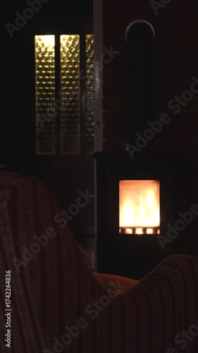 Oven with glass window and fire inside. Chair in the foreground. 