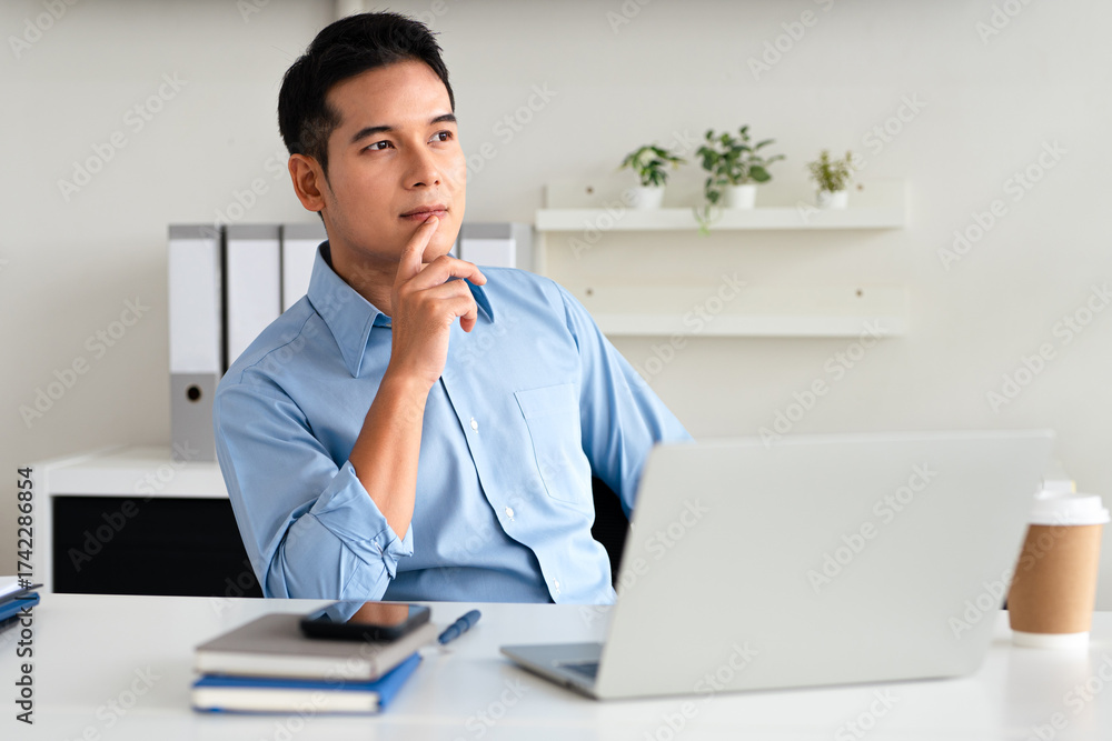 Naklejka premium young successful man, businessman, freelancer, designer in the office confidently looking to the side thinking of success, leadership, corporate growth.