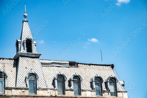 An ornate historic European building from the early 20th century with a detailed mansard roof against a clear sky