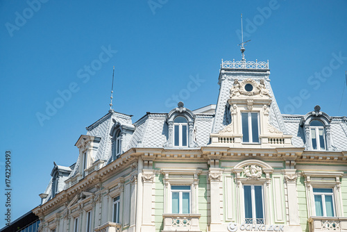 An ornate historic European building from the early 20th century with a detailed mansard roof against a clear sky