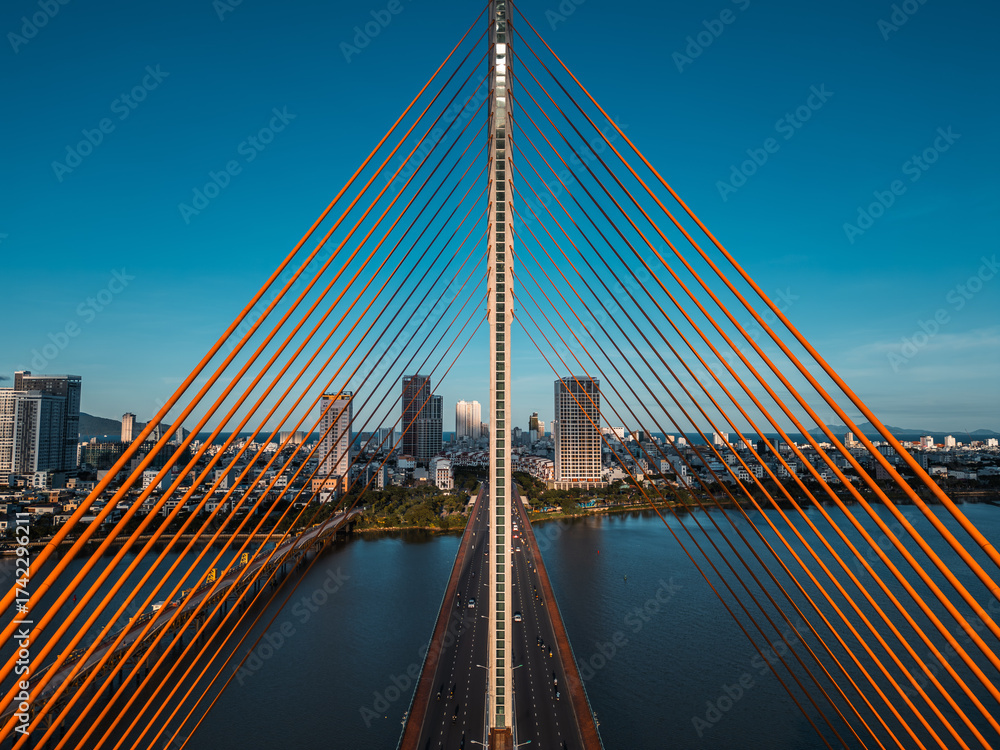 Naklejka premium Symmetric modern cable-stayed bridge over Han River in Da Nang, Contemporary urban span connecting city skyline across Vietnamese waterway