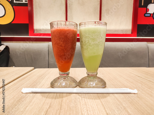 Beverage photography themes. A glass of strawberry juice and a glass of melon juice photographed side by side at a fast food restaurant. Cold juice beverage dish. Graphic Resources
