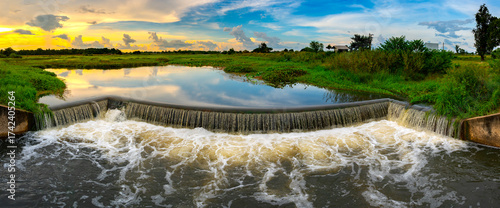 The evening sun at the dam slows down the water flowing through the weir.