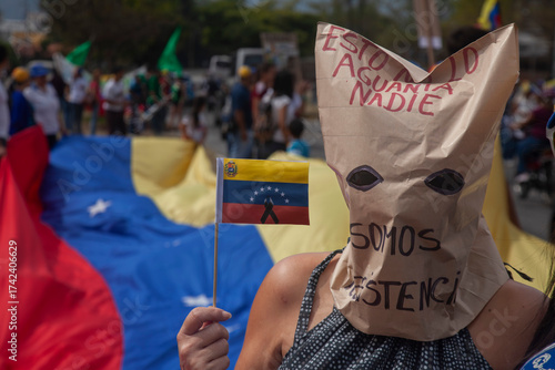Protester wearing a mask and carrying a Venezuelan flag during a citizen protest.
