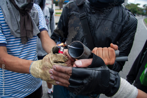 Hands lighting a homemade device at a street protest in Venezuela.
