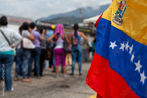 Unrecognizable women with their backs to the Venezuelan flag