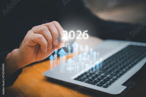 Businessman drawing digital growth arrows and bar graph with 2026 target. Futuristic concept for business goals, technology strategy, data-driven planning, success and innovation.