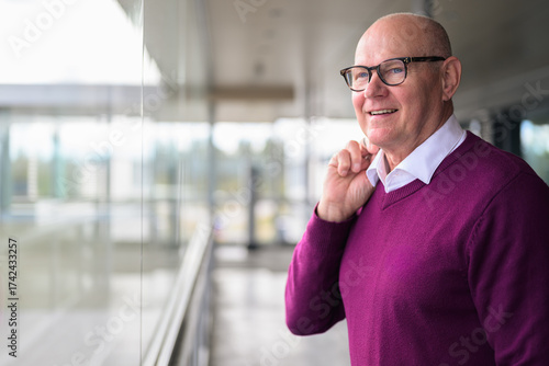 Portrait of a senior Scandinavian man wearing eyeglasses and a purple sweater