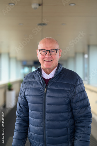 Portrait of a smiling senior Scandinavian man wearing eyeglasses in an airport corridor
