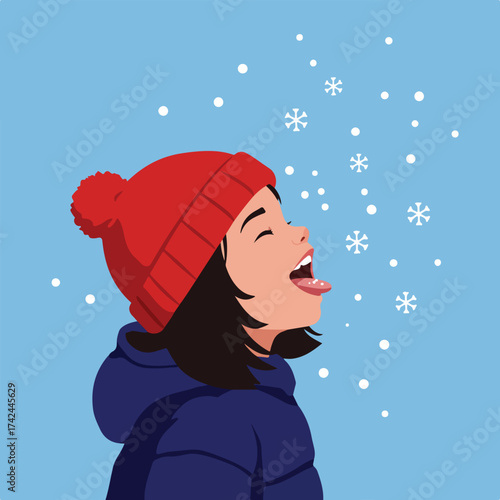 Young child in a red hat catches snowflakes on her tongue in a winter wonderland