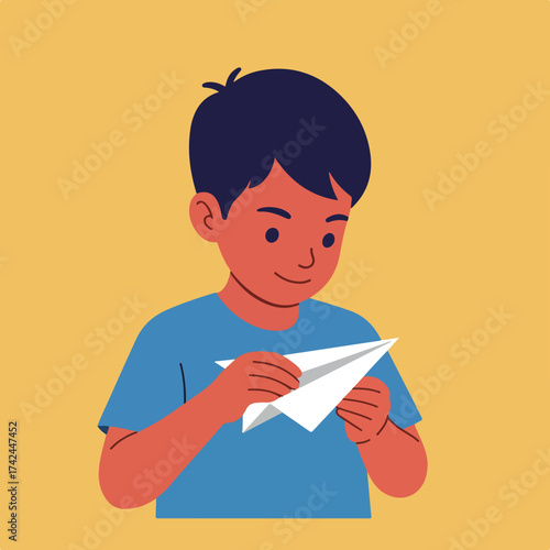 A boy in a blue shirt focuses as he folds a white paper airplane