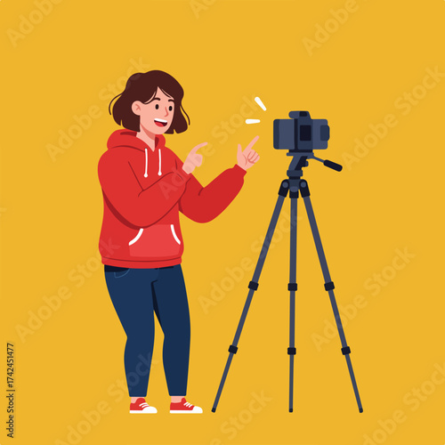 Person in red hoodie films with camera on tripod