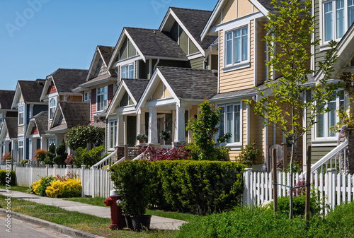 Bright suburban street lined with colorful homes and lush gardens in a clear blue sky